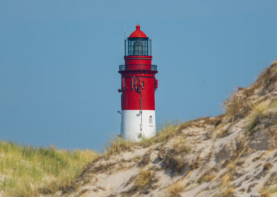 Rot weißer Leuchtturm mit Sanddünne.